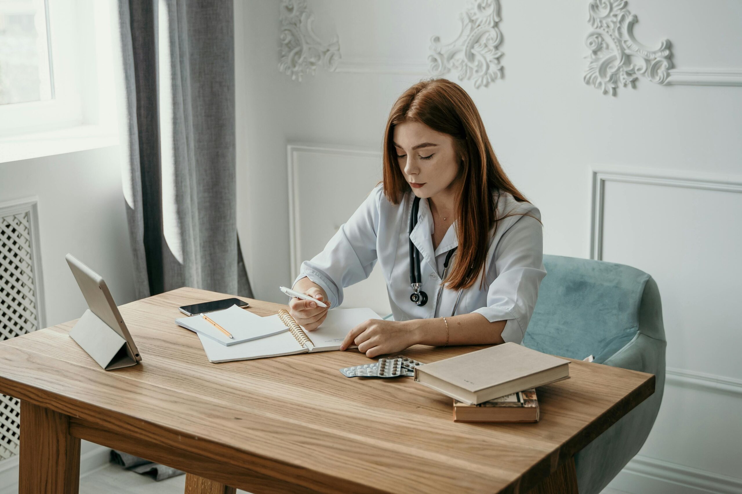 how to get more patients with a book – female doctor sitting at desk writing a book how to get more patients with a book - female doctor sitting at desk writing a book